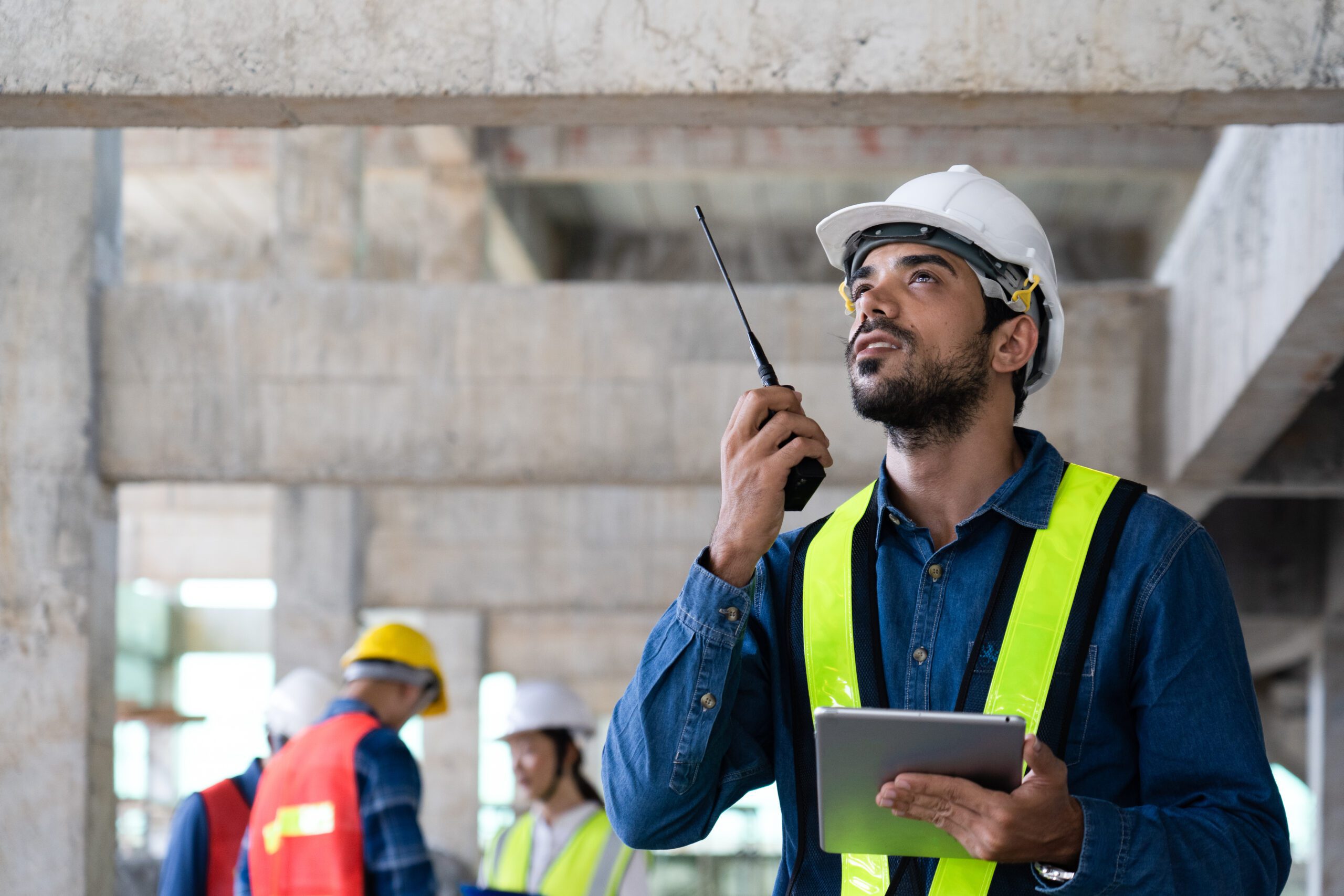 maintenance manager using walkie-talkie to communicate safety and quality control policy with workers on site, civil engineer informs infrastructure and building construction progress to supervisor