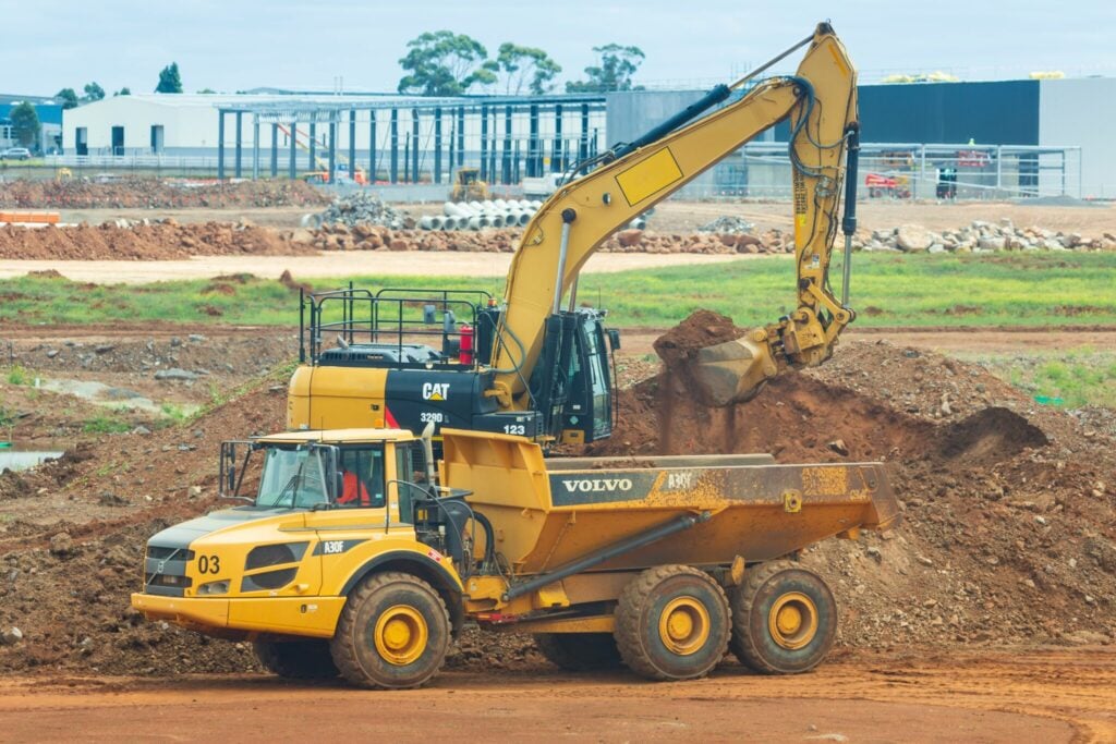 Excavator loading soil into a dump truck at a construction site.