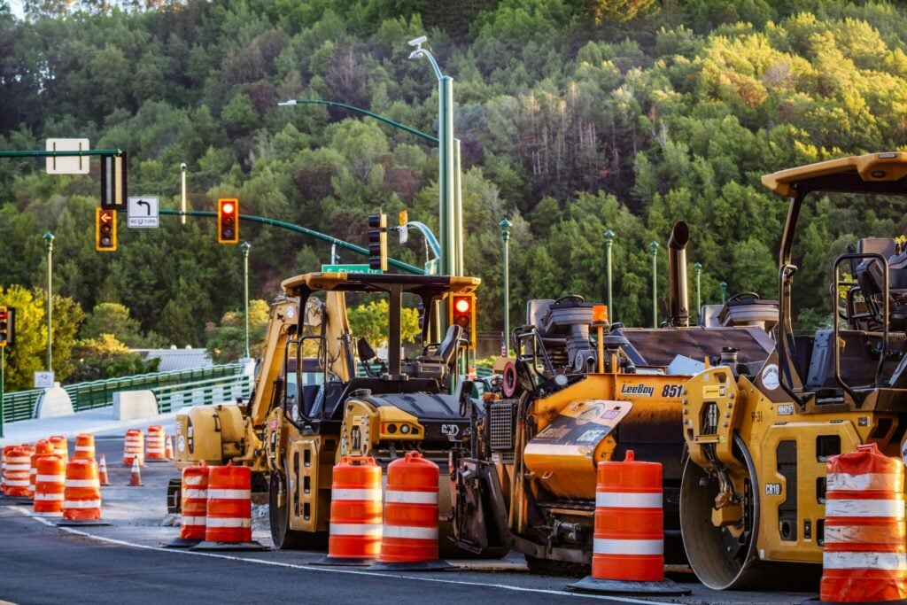 Road construction site with heavy machinery and safety barriers.
