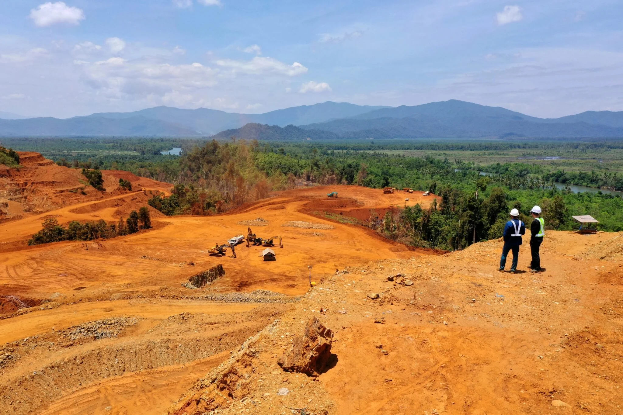 Active earthworks site with heavy machinery and workers overseeing land preparation.
