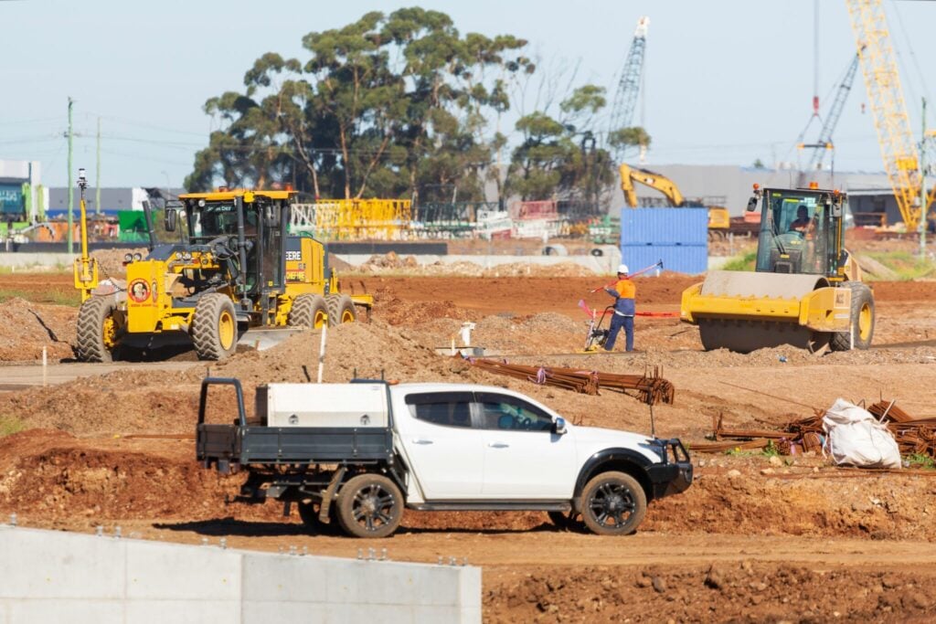 Large construction site with graders, rollers, and site vehicles.