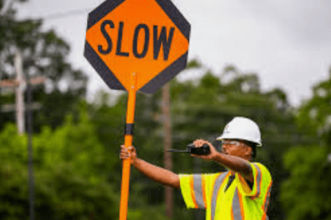Traffic controller holding a slow sign at a road construction site.
