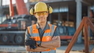 Construction worker wearing a hard hat and high-vis vest standing on a worksite.