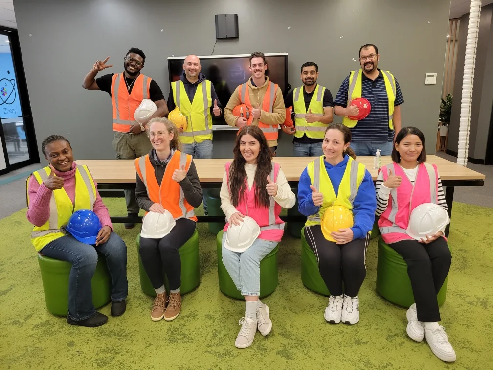 Group of students wearing high-vis vests and holding hard hats after completing White Card training in a classroom.
