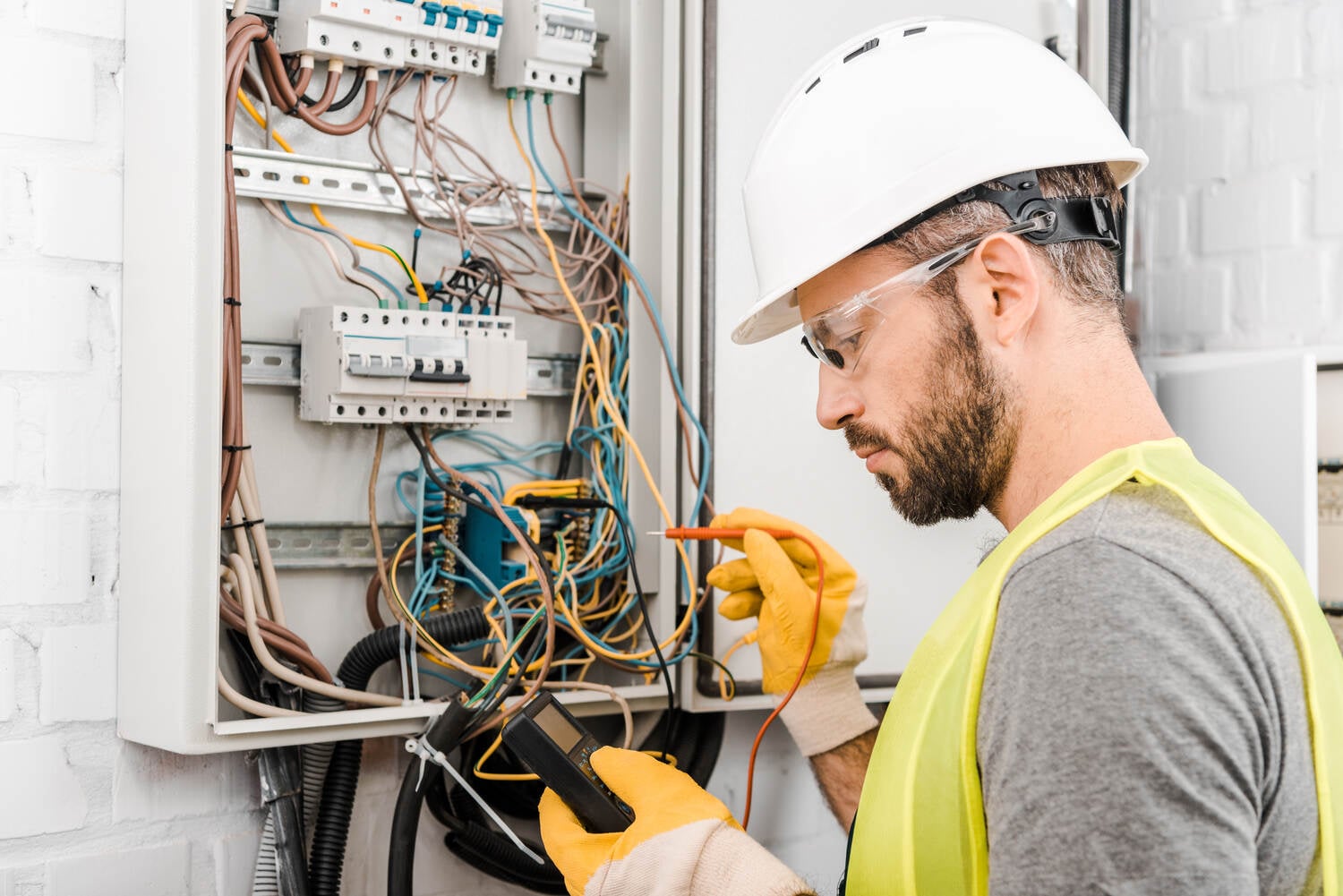 Electrician checking electrical box with multimetr in corridor